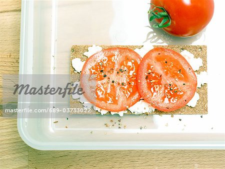 Crispbread with cream cheese, tomato and pepper in food storage container