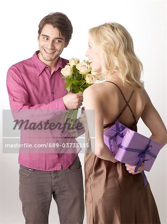 Woman with gift and man with bunch of flowers