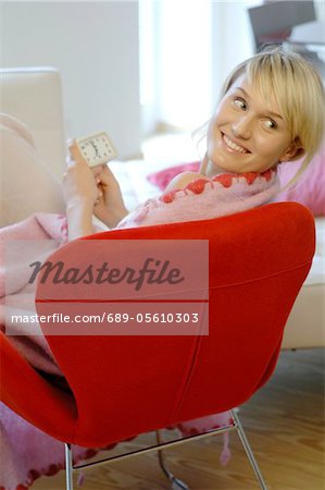 Relaxed young woman with alarm clock at home