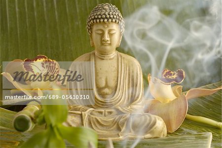 Buddha statuette with blossoms and smoke