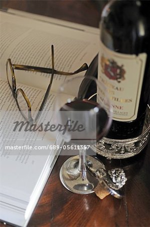 Glass of red wine, book and glasses