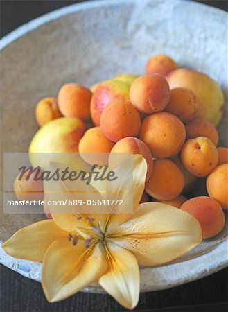 Apricots, apples and lily blossom in a bowl