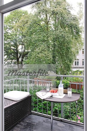 Milk, strawberries, eyeglasses and newspaper on balcony table