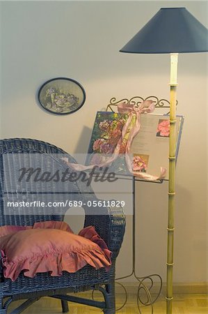 Wicker chair, floor lamp and book with flowers