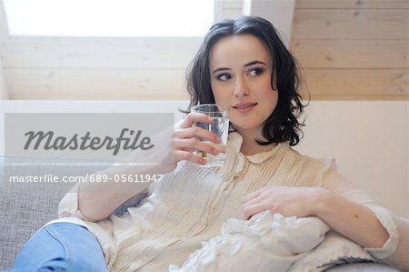 Young woman on couch drinking glass of water