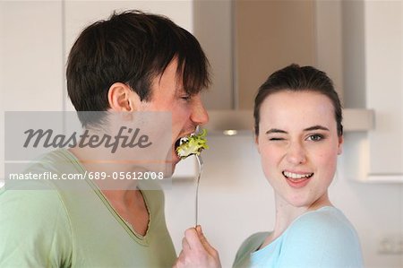 Young woman feeding man with salad