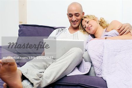 Happy couple on couch using laptop