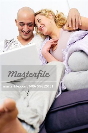Happy couple on couch using laptop
