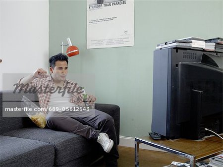 Man watching TV with beer and chips Man watching TV with beer and chips