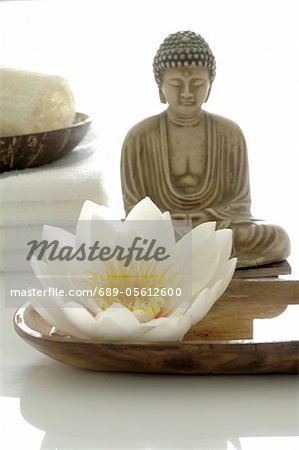 White water lily blossom, Buddha statuette and towels White water lily blossom, Buddha statuette and towels