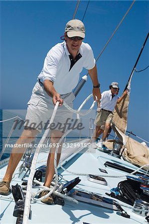 Sailors working ropes on Deck of yacht