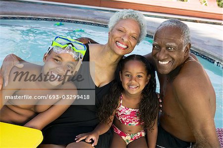 Girl (5-6), boy (10-12) with grandparents at swimming pool, portrait.