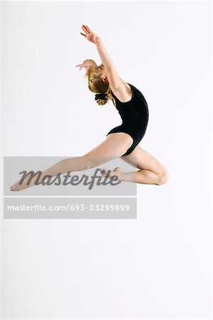 Gymnast (16-17) leaping in air, side view