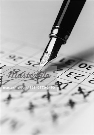Tip of fountain pen marking date in calendar, (b&w), (close-up)