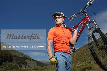 Cyclist carrying bike in countryside