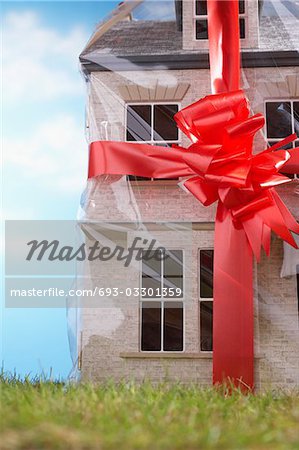 https://image1.masterfile.com/getImage/693-03301359em-model-house-giftwrapped-with-red-ribbon-and-bow-closeup-stock-photo.jpg