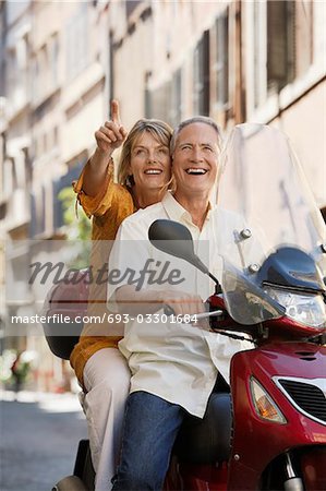 Middle-aged couple sightseeing on scooter in Rome, Italy