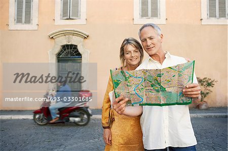 Couple on street looking at map in Rome, Italy, front view