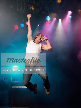 Young Man Singing and jumping on stage at concert, low angle view