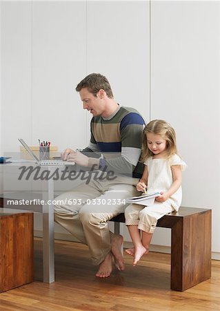 Father and daughter drawing and using laptop