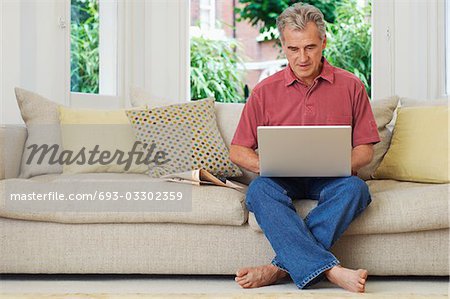 Man using laptop, sat on sofa