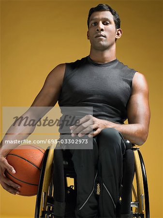 Paraplegic athlete sitting in wheelchair holding basketball