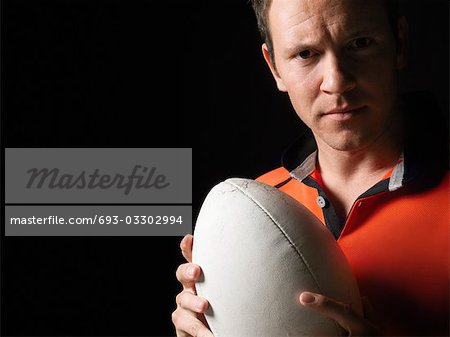 Rugby player holding ball, close-up, portrait