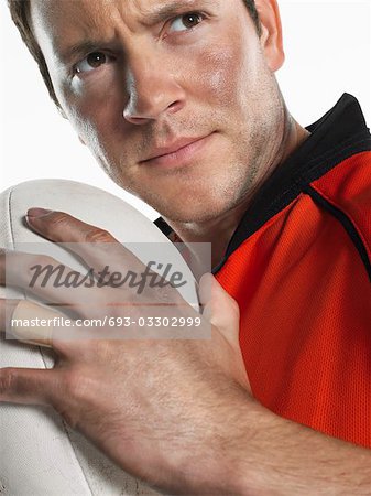 Rugby player holding ball, close-up, portrait