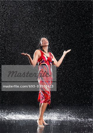 Woman, arms raised, smiling, standing in rain