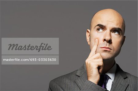 Bald businessman with hand on chin, thinking