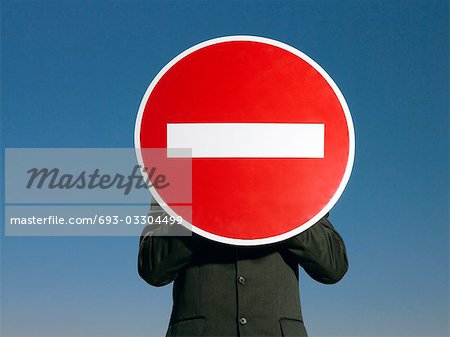 Man in suit holding 'no entry' sign in front of face, half length