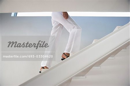 Woman walking up staircase indoors, low section