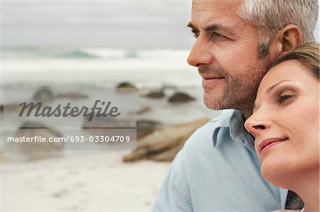 Close up of couple on beach, woman resting her head on man's shoulder