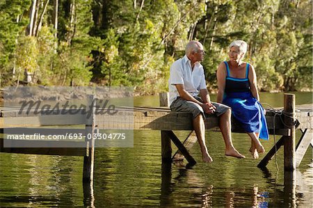 Senior Couple sitting on dock by lake.