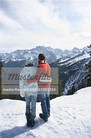 Couple looking at view from mountain peak, back view