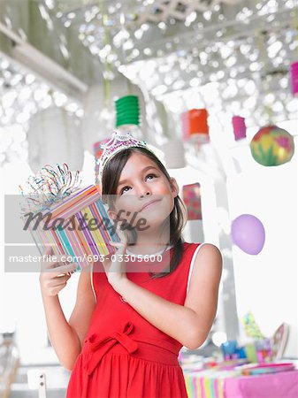 Portrait of girl (7-9) holding birthday present at party