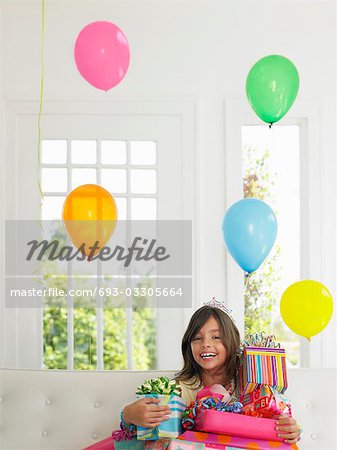 Portrait of young girl (7-9) with birthday presents, smiling