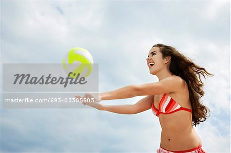 Teenage girl (16-17) playing beach volleyball, low angle view