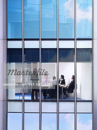 Group of business people at meeting in office, view from building exterior