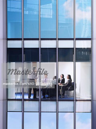 Group of business people at meeting in office, view from building exterior