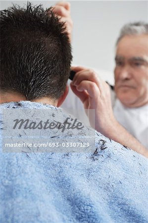 Barber cutting mans hair in barber shop, close-up