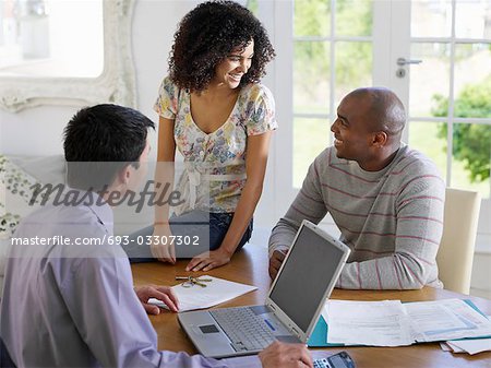 Couple sitting at dining table with financial advisor, elevated view