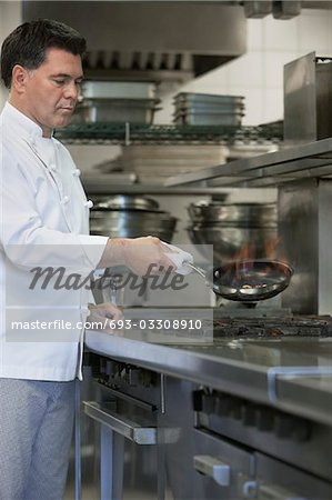 Chef cooking food using frying pan in kitchen