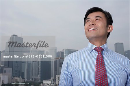 Portrait of young business man, office buildings in background