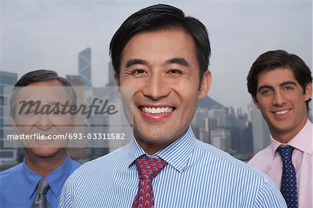 Portrait of three business men, office building in background