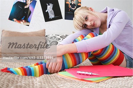 Portrait of teenage girl (16-17) sitting on bed, smiling