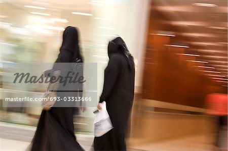 Dubai, UAE, Two women dressed in traditional abayas and hijabs, black robes and scarves.