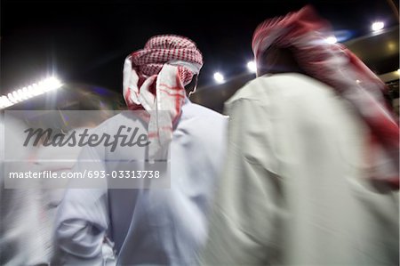 Dubai, UAE, small group of traditionally dressed Muslim men roaming grounds at Nad Al Sheba