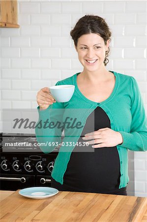 Pregnant woman drinking tea in kitchen