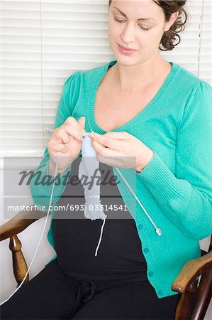 Pregnant woman knitting in chair